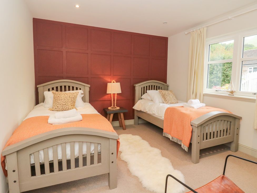 A bedroom with two beds and a window at Ghillie's Cottage in Killin