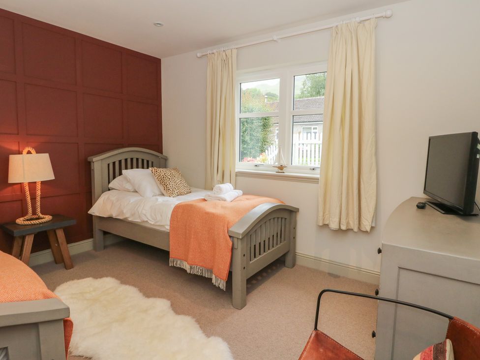 A bedroom with beds and a television at Ghillie's Cottage in Killin