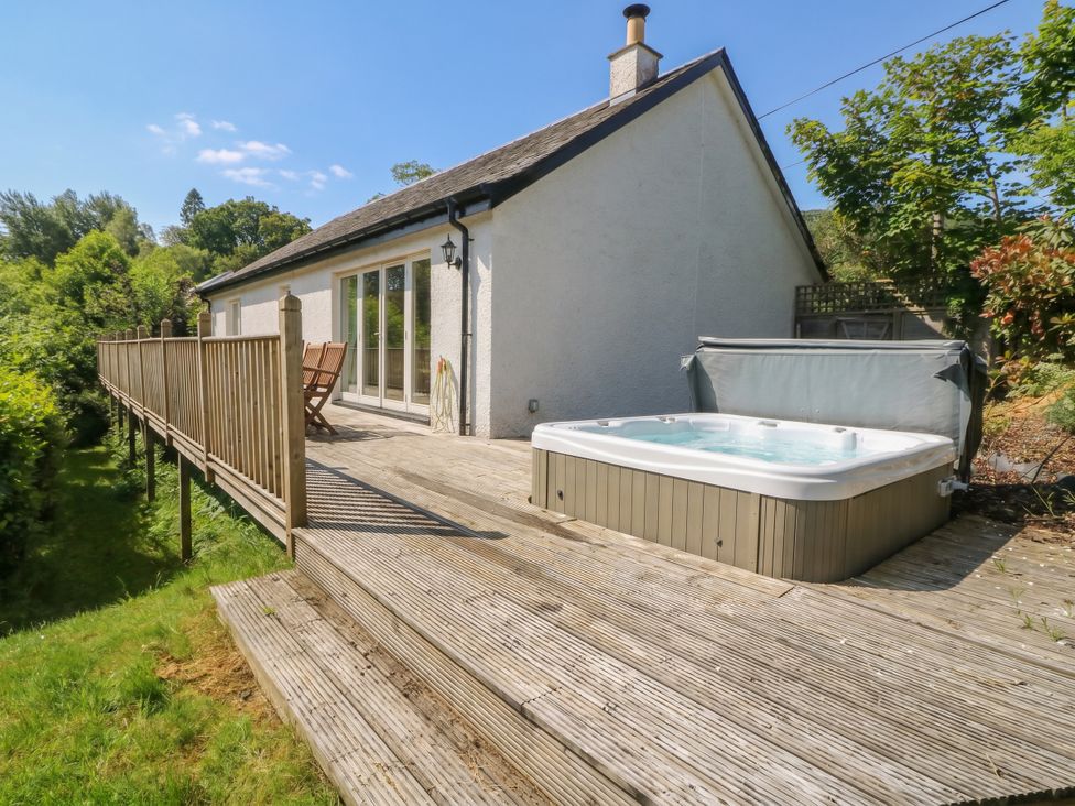 An outdoor deck with a hot tub at Ghillie's Cottage in Killin