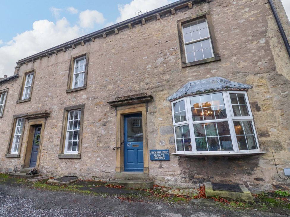 An exterior view of Devonshire House in Settle with windows and a blue door