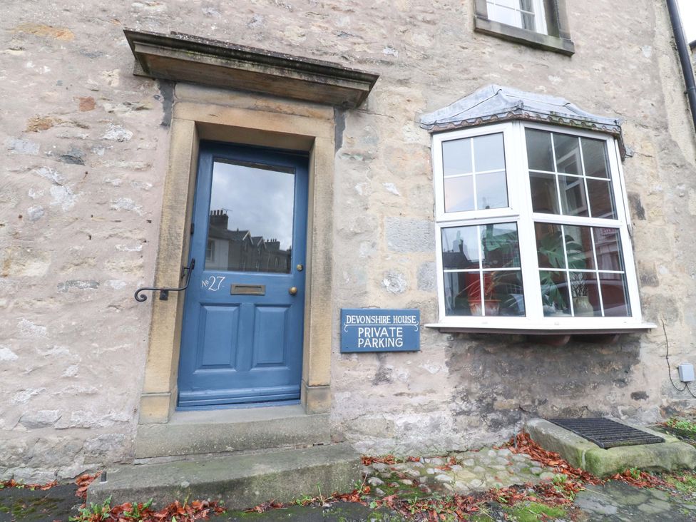 An exterior view of Devonshire House with a blue door and a sign for private parking in Settle