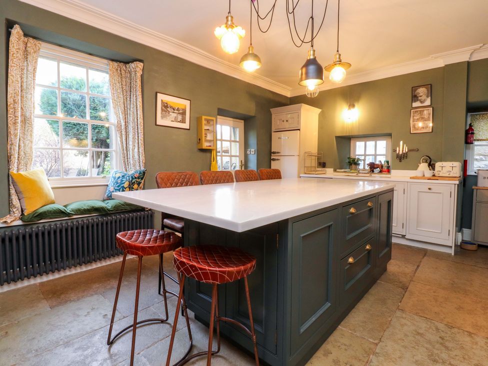 A kitchen with an island and stools at Devonshire House in Settle