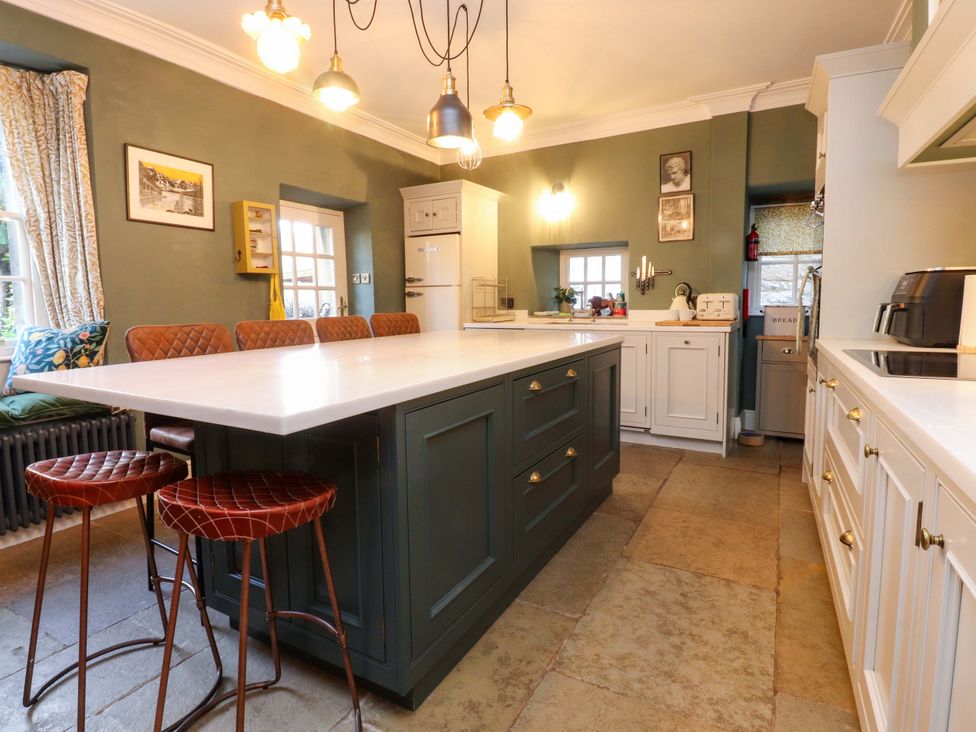 A kitchen with an island and stools at Devonshire House in Settle
