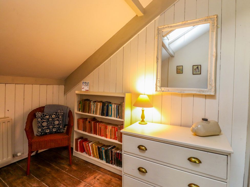 An attic space with a bookshelf and a mirror at Devonshire House in Settle