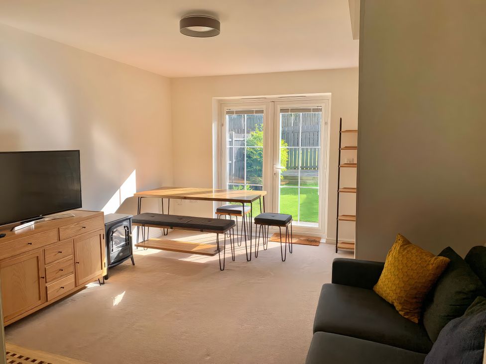 A living room with a table and stools at 23 Wheathouse Grove
