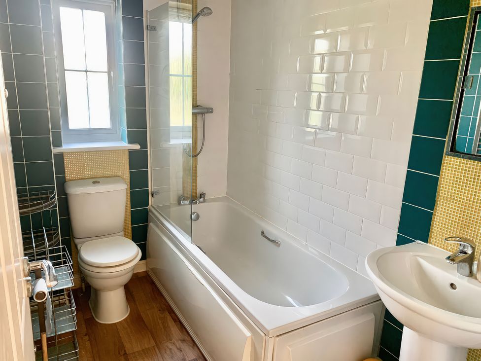 A bathroom with a bathtub, toilet, sink, and window at 23 Wheathouse Grove