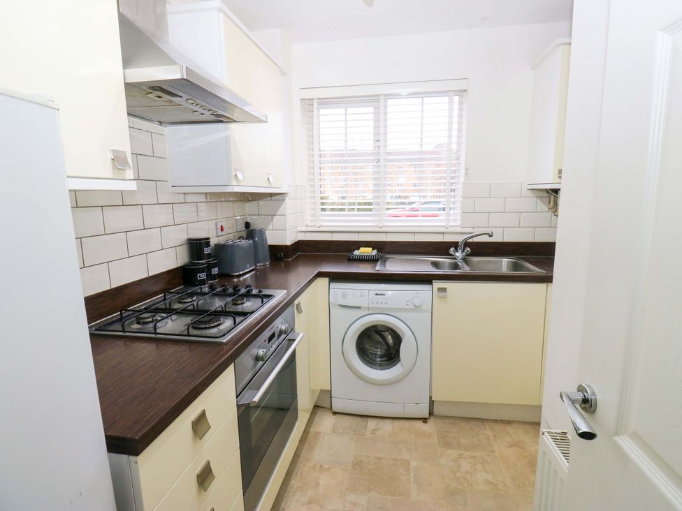 A kitchen with a fridge, stove, and washing machine at Cottage Holiday Home in Huddersfield