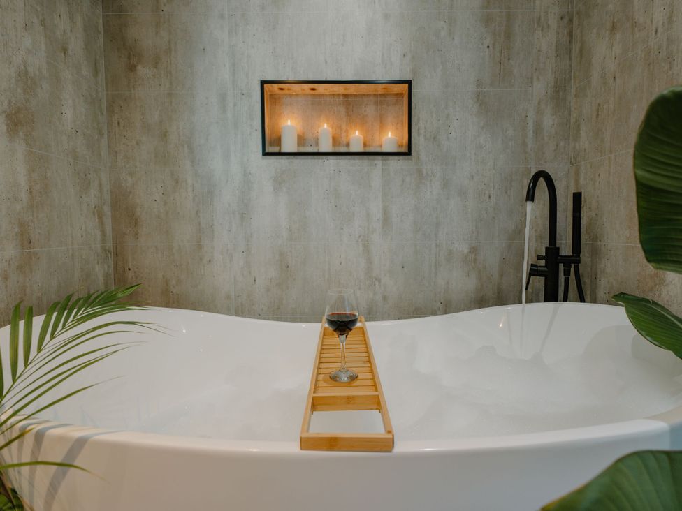 A bathroom with a bathtub and candles in a display at The Elton in Kings Cliffe