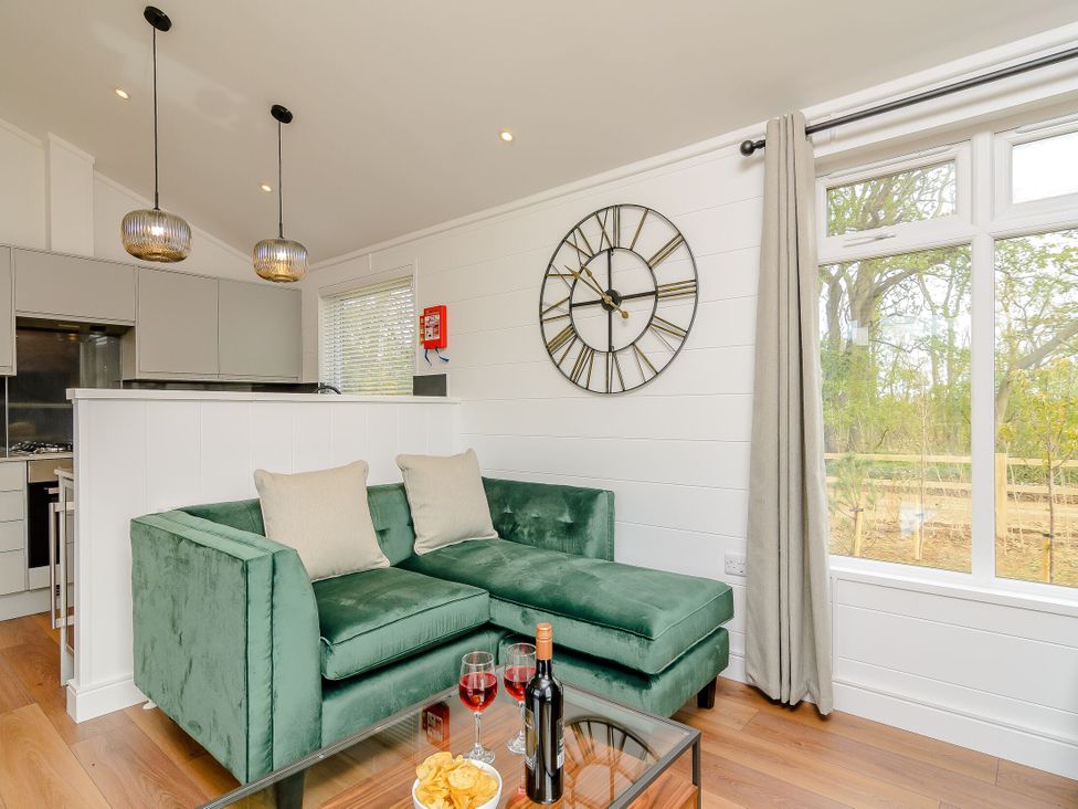 A living room with a green sofa and table at The Castor in Kings Cliffe