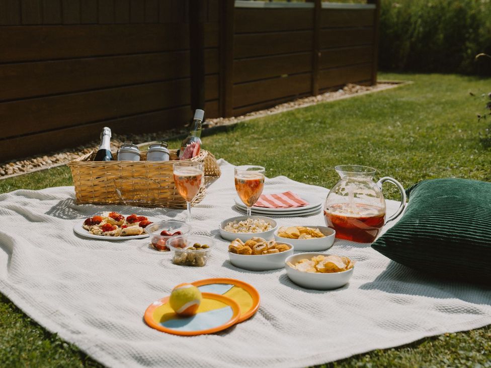 A picnic setup with snacks and drinks on a blanket in the garden at The Castor in Kings Cliffe