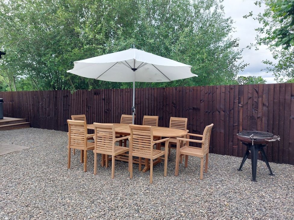 A garden with a wooden table and chairs under an umbrella at 1 Clarkes Lane St Martins