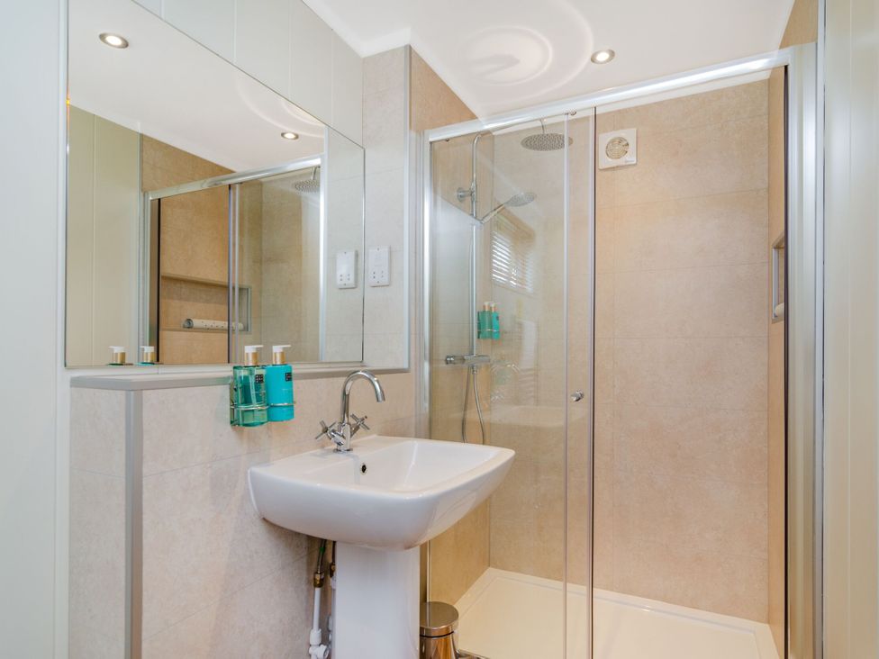 A bathroom with a shower, sink, and mirror at The Kingscliffe (Pet) Kings Cliffe