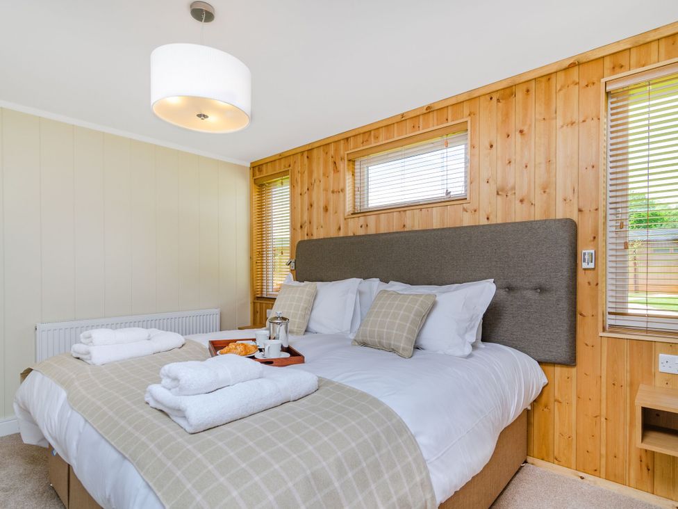 A bedroom with a bed and windows at The Kingscliffe (Pet) in Kings Cliffe