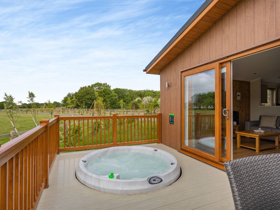 A hot tub on the deck with wooden railing at The Kingscliffe (Pet) in Kings Cliffe
