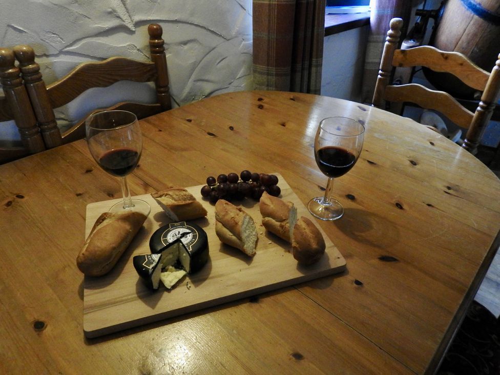 A dining room with bread, cheese, grapes, and wine on a table at Ramsgrove in Swansea