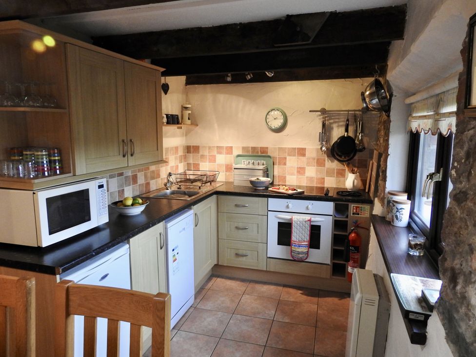 A kitchen with cabinets, sink, stove, and microwave at Ramsgrove in Swansea