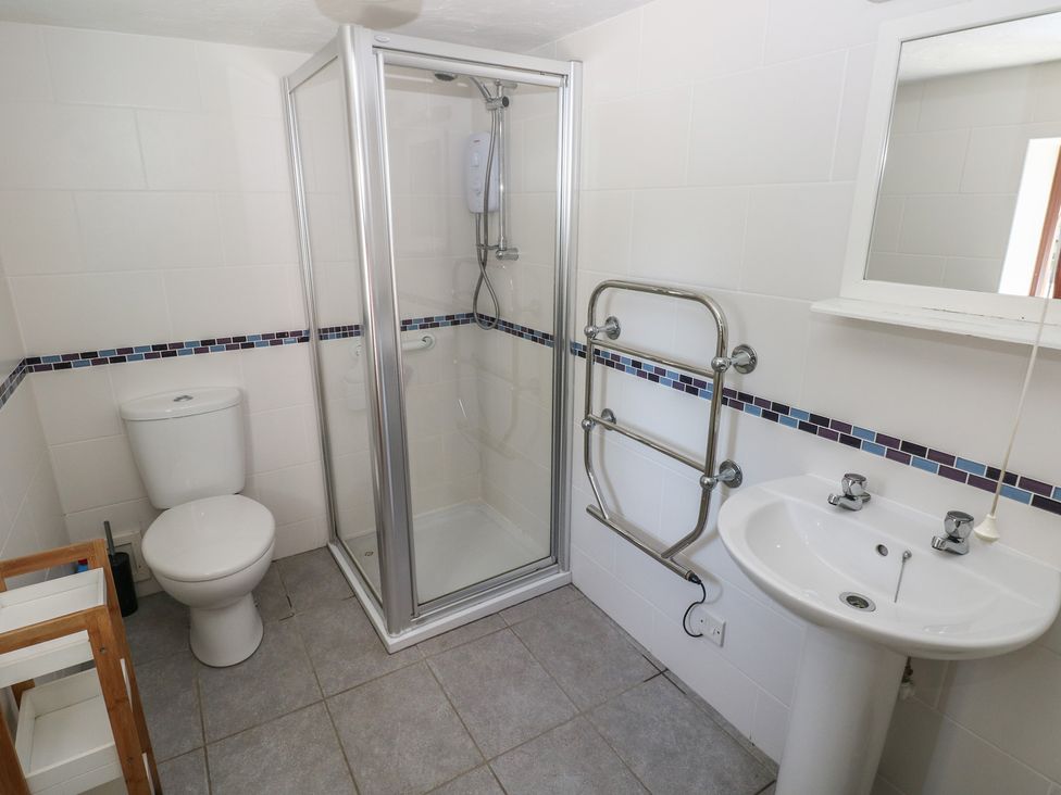 A bathroom with a shower, toilet, wash basin, and towel rail at Ramsgrove in Pilton