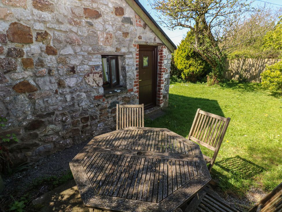 An outdoor setting with a table and chairs near a stone wall at Ramsgrove in Pilton