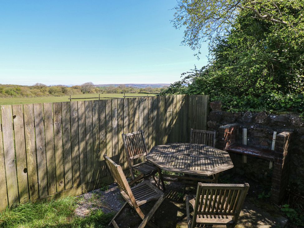 An outdoor seating area with a wooden table and chairs at Ramsgrove in Pilton