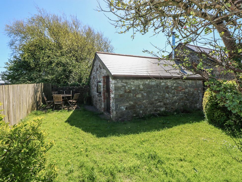 A garden with a stone shed and wooden furniture at Ramsgrove in Pilton