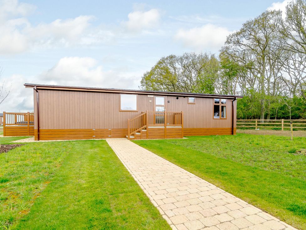 A wooden cabin with a pathway and grass at The Wansford in Kings Cliffe
