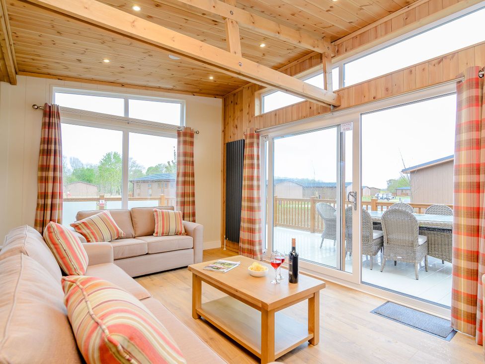 A living room with a sofa, coffee table, and large windows at The Wansford in Kings Cliffe