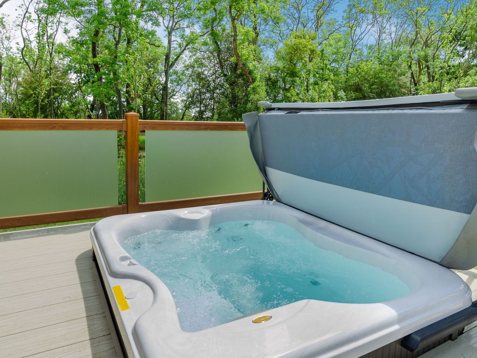 A hot tub on a deck with trees around at The Wansford (Pet) Kings Cliffe