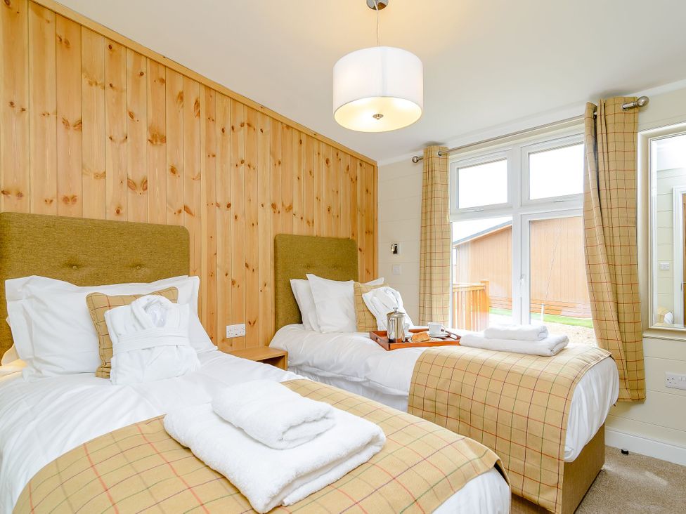 A bedroom with twin beds and a bedside table at The Wansford (Pet) in Kings Cliffe