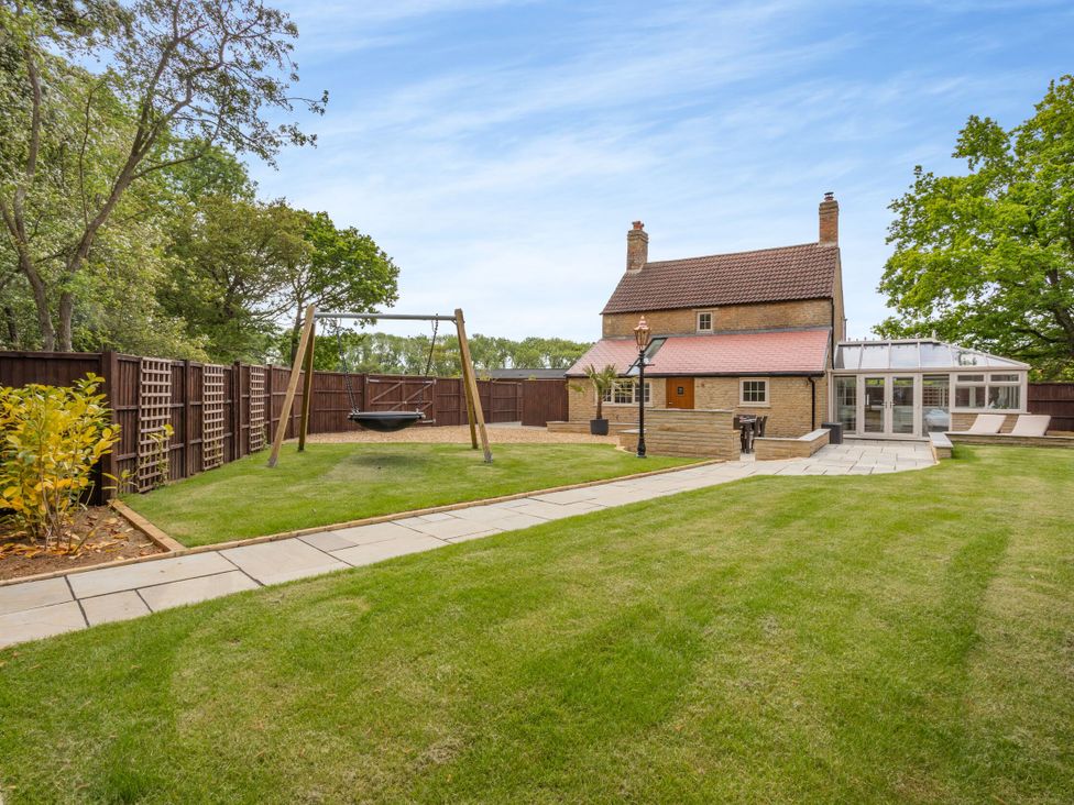 A garden with a swing set and a hammock at The Cottage in Kings Cliffe