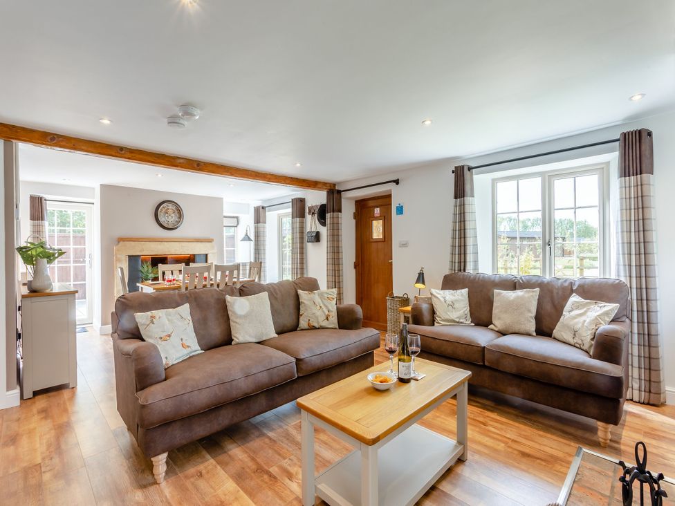 A living room with sofas and a dining table at The Cottage in Kings Cliffe