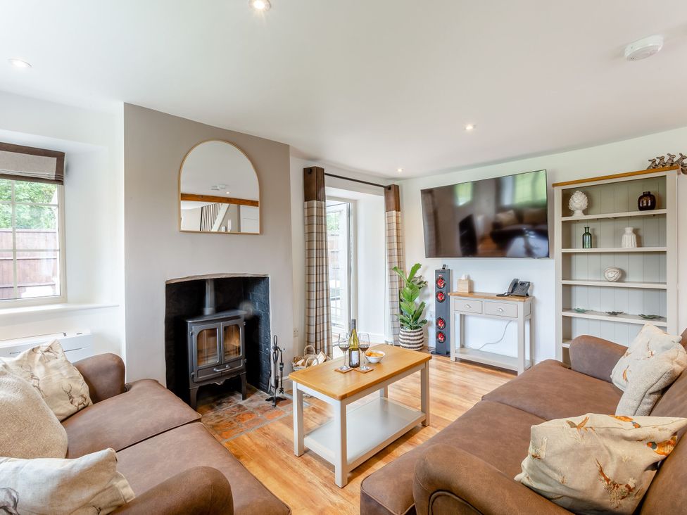 A living room with a sofa, coffee table, and television at The Cottage in Kings Cliffe