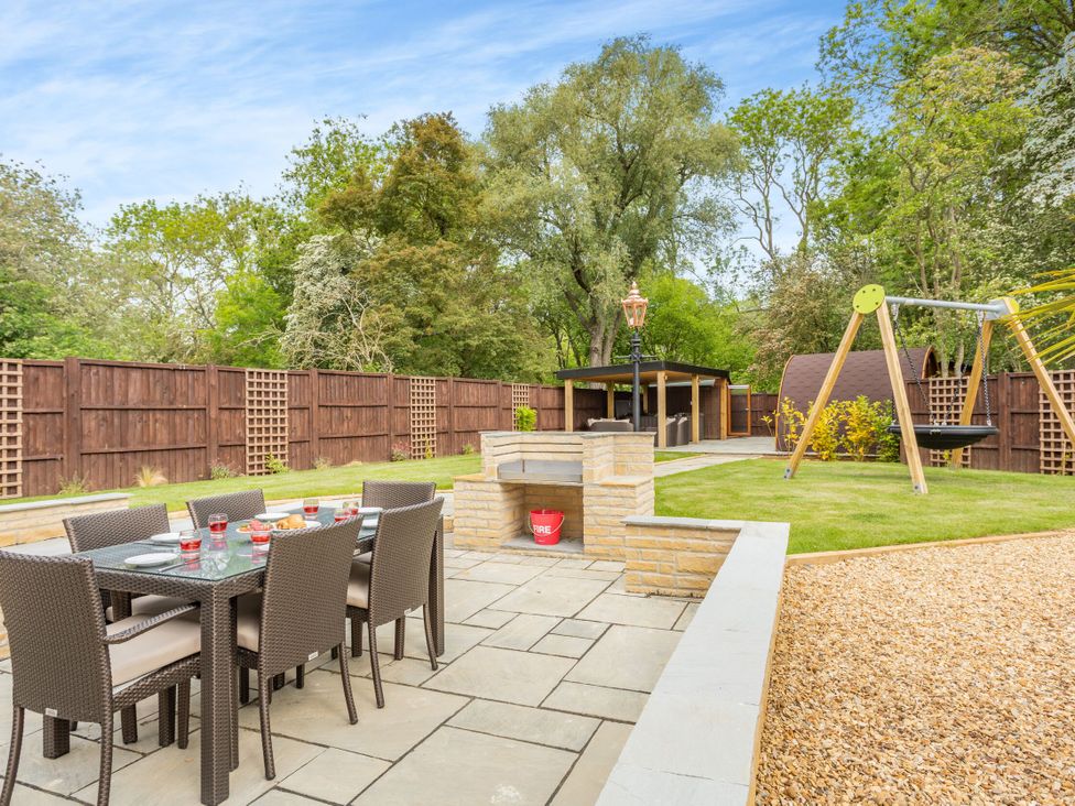An outdoor dining area with a fire pit and a swing set at The Cottage in Kings Cliffe
