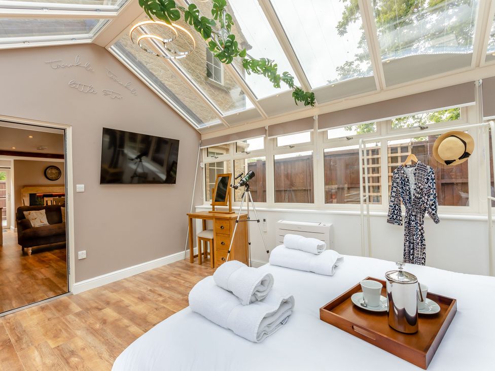 A conservatory with a bed and a desk at The Cottage in Kings Cliffe