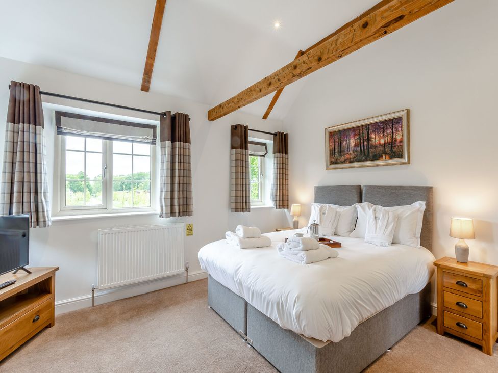 A bedroom with a bed and a television at The Cottage in Kings Cliffe
