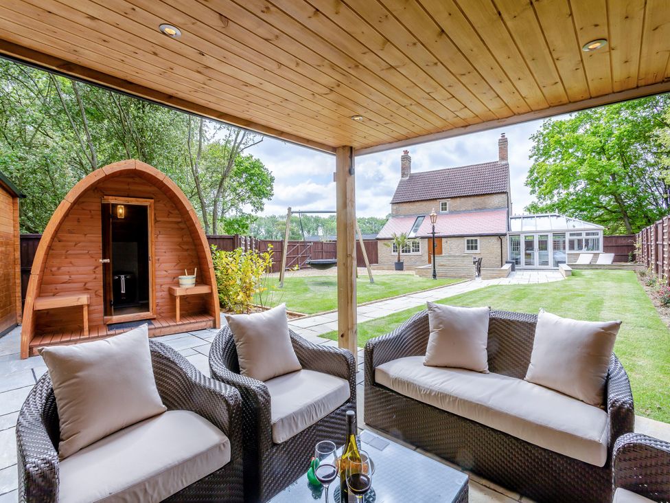 An outdoor seating area with a wooden pod and garden at The Cottage in Kings Cliffe