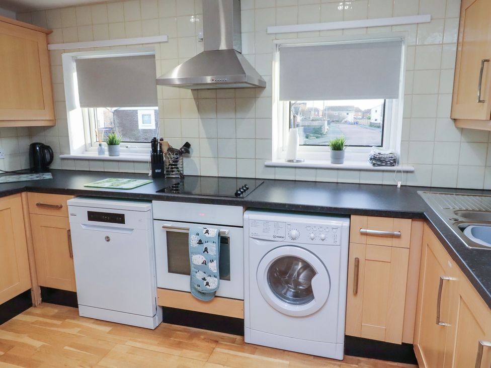 A kitchen with appliances including a dishwasher and washing machine at Beadlin cottage Beadnell