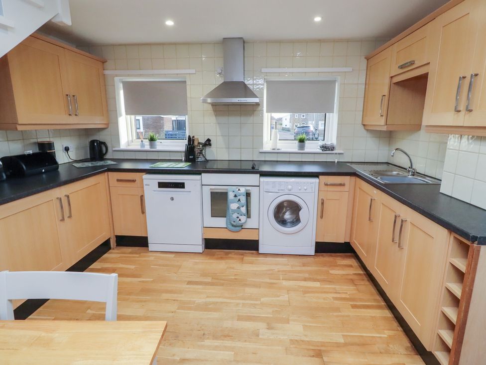 A kitchen with appliances and wooden cabinets at Beadlin cottage Beadnell