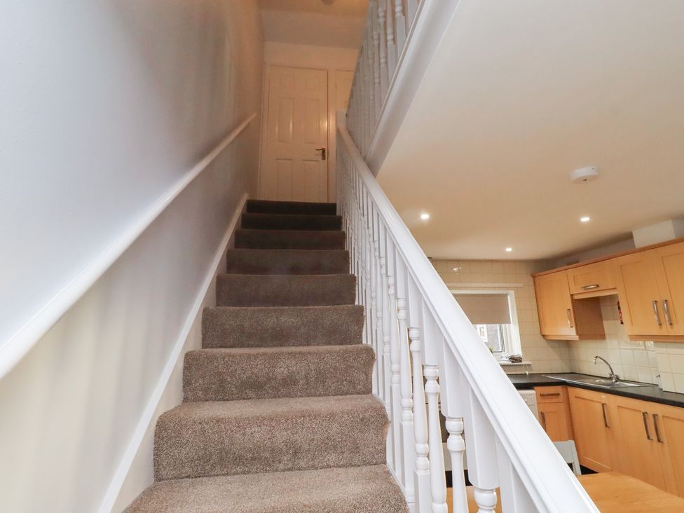 A staircase leading to a landing with a door at Beadlin cottage Beadnell