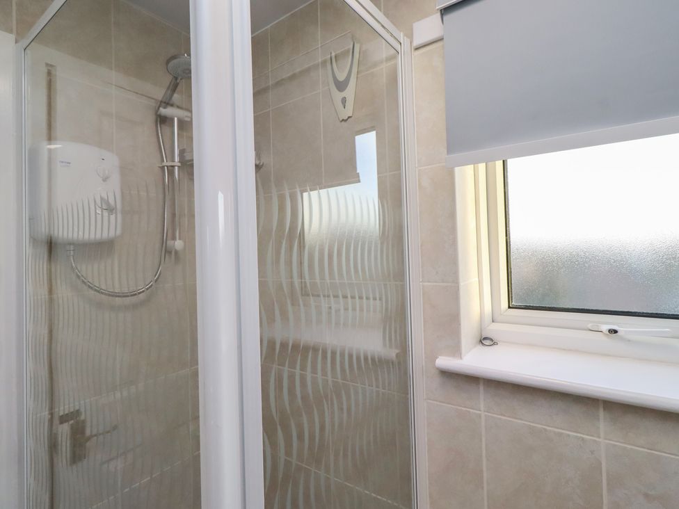 A shower area with window and showerhead at Beadlin cottage Beadnell