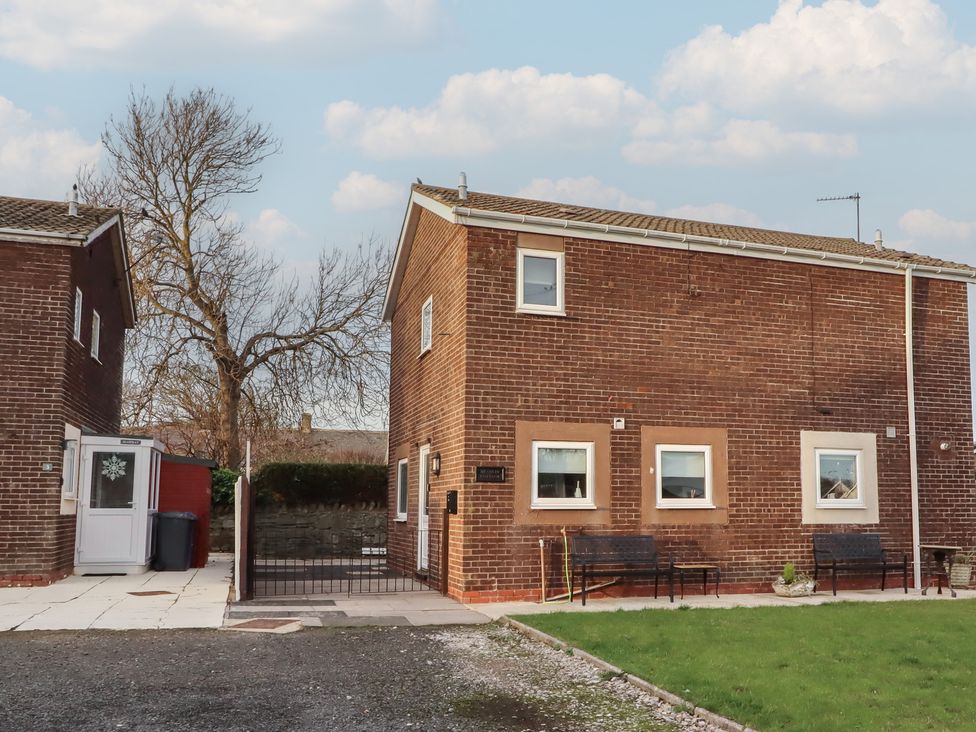 A brick house with benches in the outdoor area at Beadlin cottage Beadnell