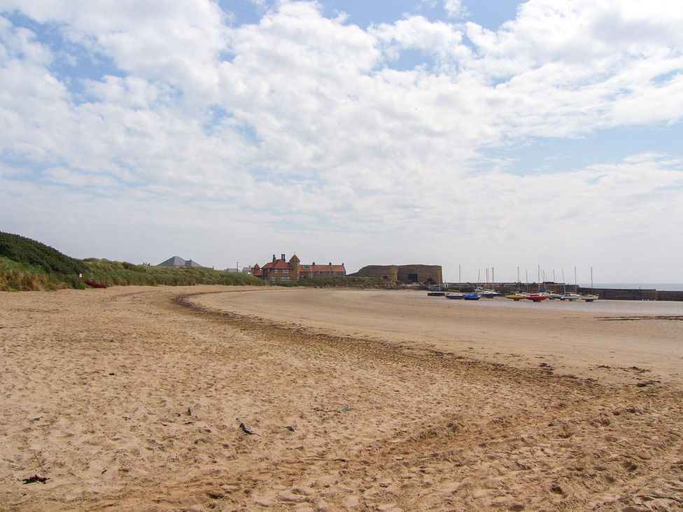 A beach with sand and boats at Beadlin cottage in Beadnell