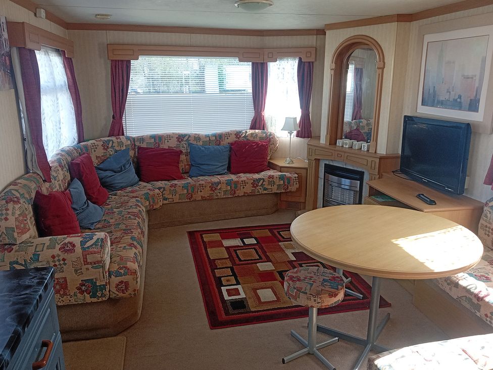 A living room with a sofa, table, and television at Atlas Moonstone in Ingoldmells