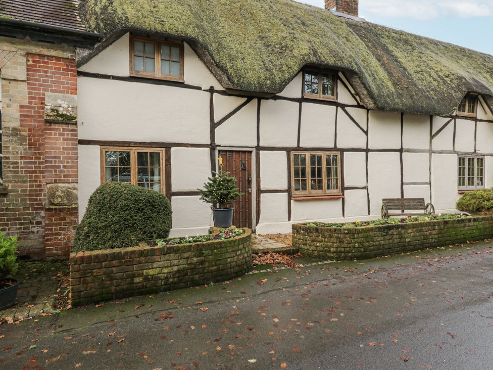 An exterior view of a cottage with a thatched roof and brick wall at 24 Eastcourt 