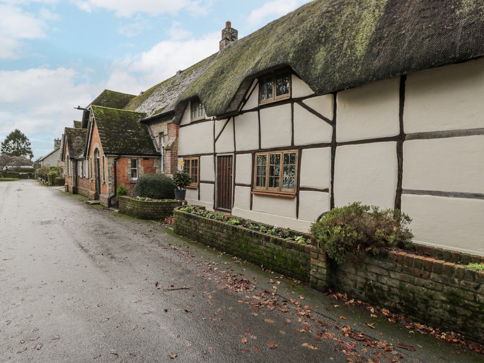 A house with a thatched roof and brick wall on a street at 24 Eastcourt