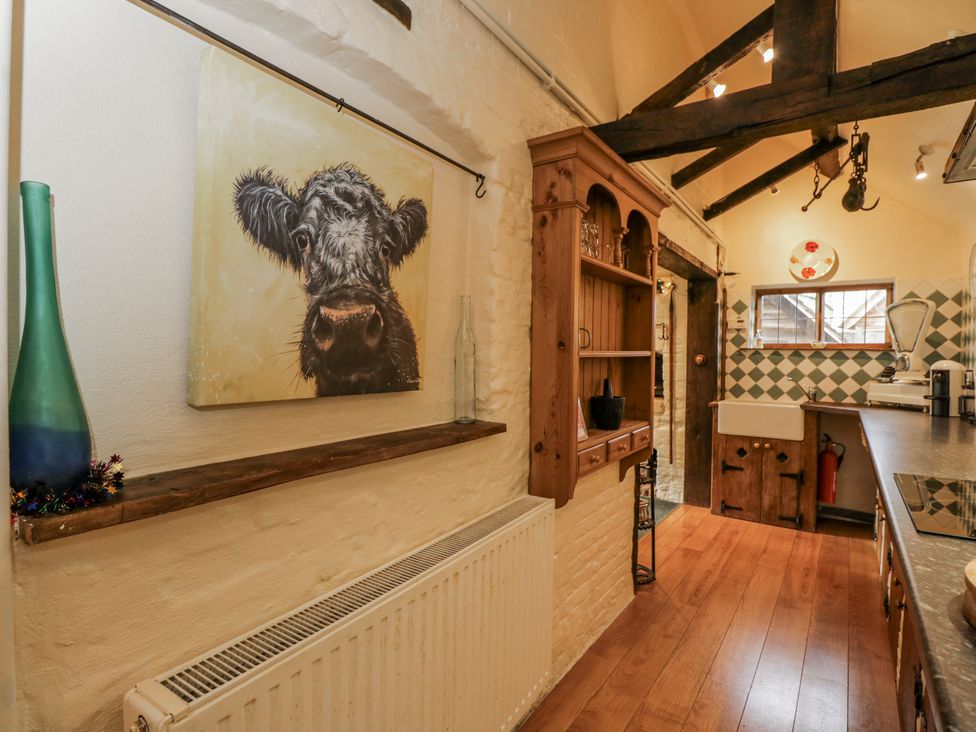A kitchen with a cow painting and wooden cabinetry at 24 Eastcourt