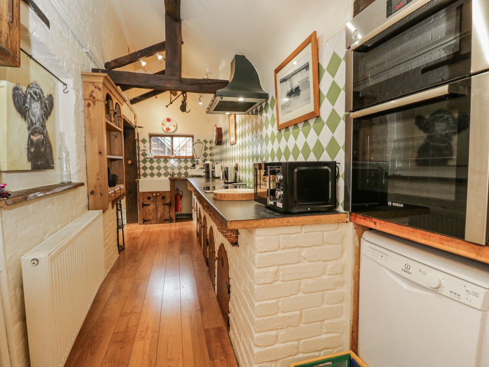 A kitchen with various appliances and wooden shelves at 24 Eastcourt