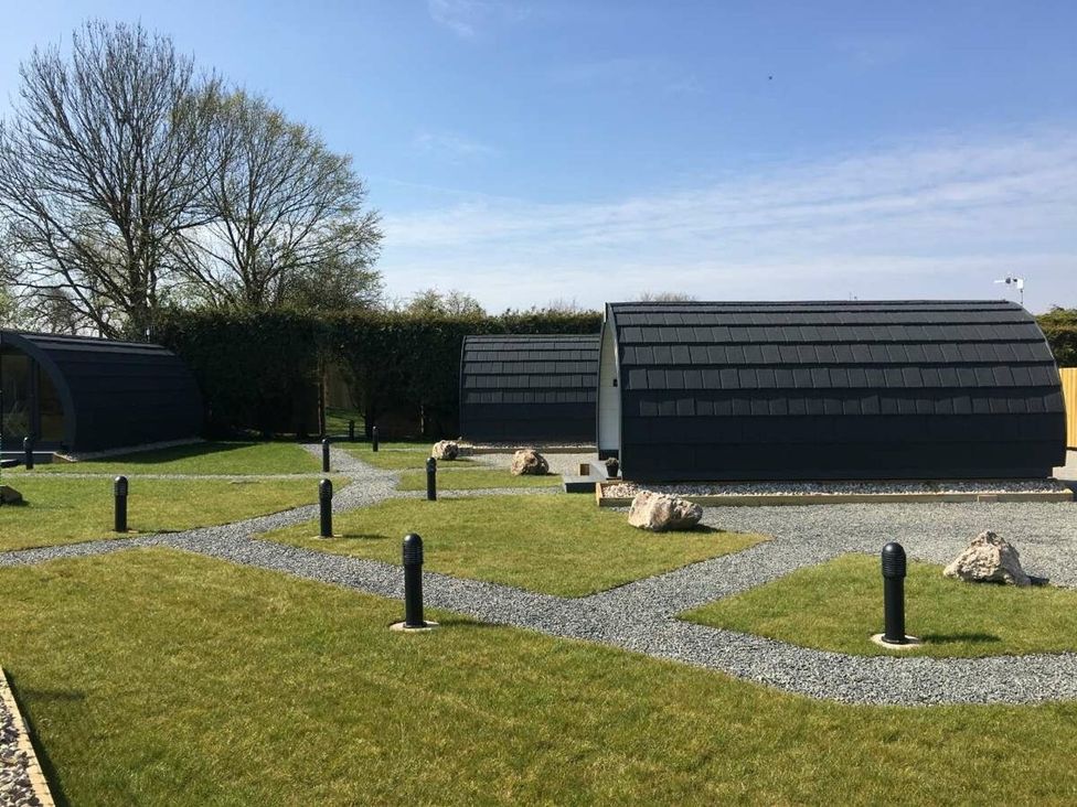 An outdoor area with modern cabins and a gravel pathway at Pod 1 (Pet Friendly) Carnforth