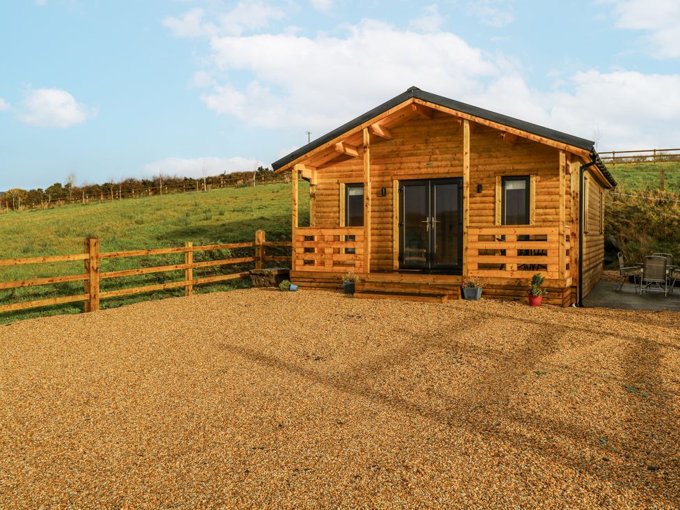 A log cabin with a gravel driveway and fence at Glenview Log Cabin in Ballycastle