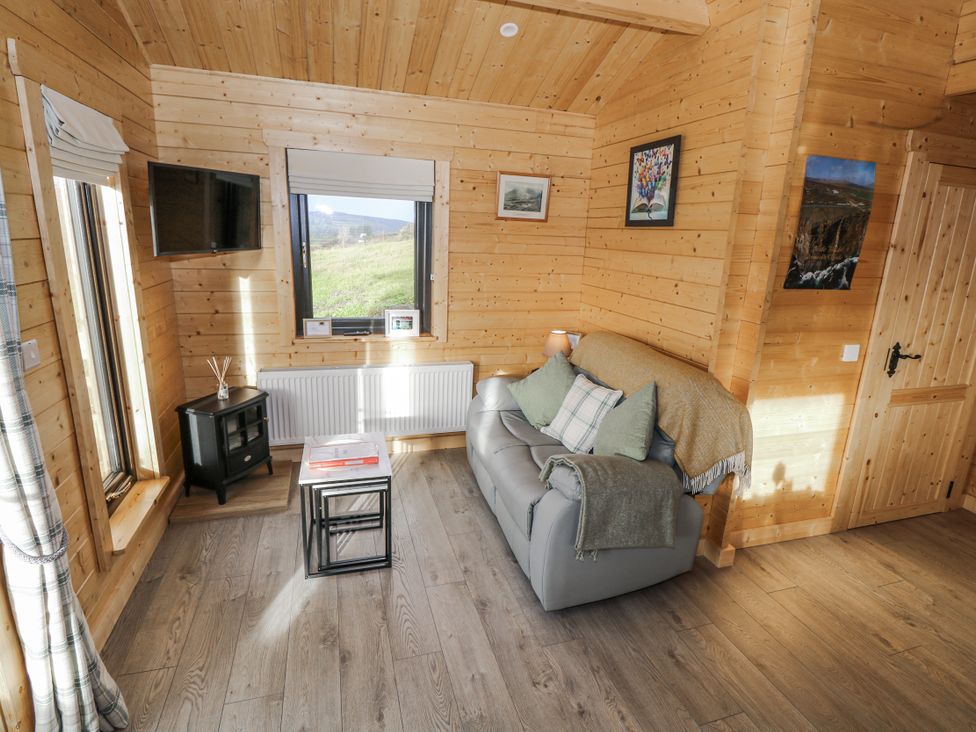 A living room with a sofa and television at Glenview Log Cabin Ballycastle