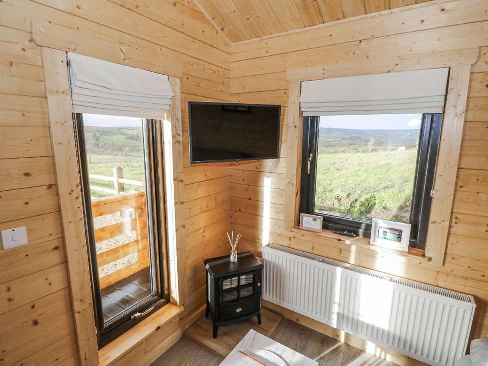 A snug with windows and a television at Glenview Log Cabin Ballycastle